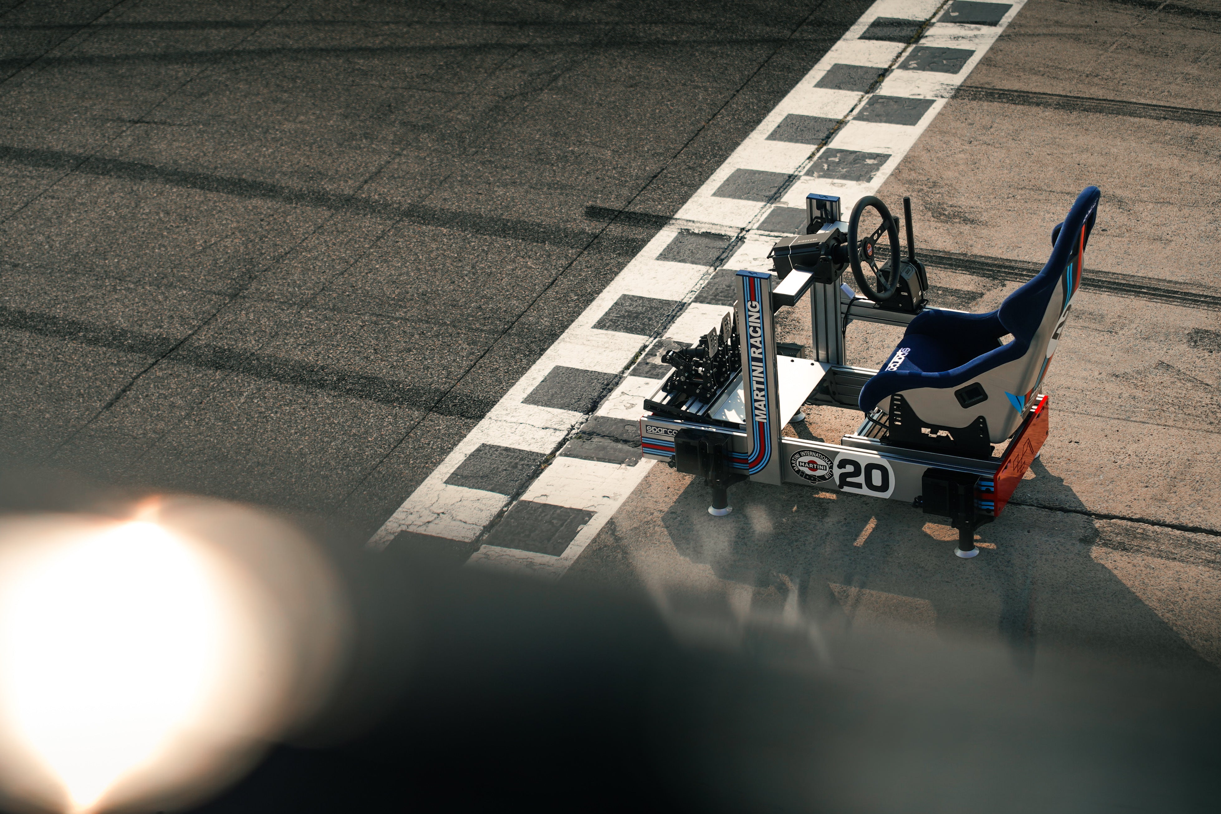 Grid One simracing cockpit med Martini Racing design på en racerbane